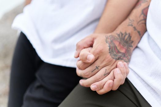 Detail of the tattooed held hands of two gay men outdoors