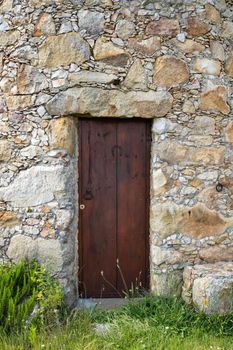 Ancient wooden door in stone wall.