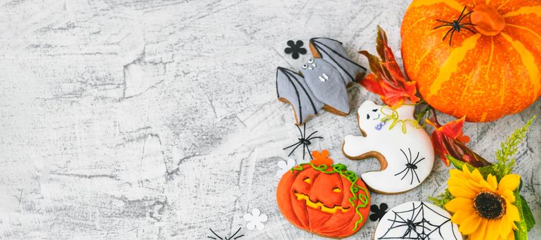 banner with Halloween background with cookies, leaves, sunflower and spiders, top view. Halloween objects on textured concrete with space for text. Flat lay. Soft focus