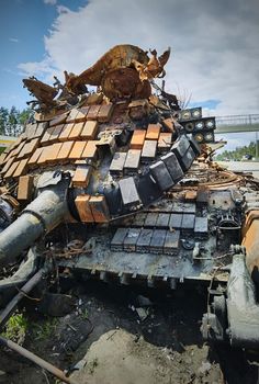 Kyiv region, Ukraine - May 15, 2022: War in Ukraine. Highway Kyiv - Zhytomyr. People take selfies against destroyed russian tank after russian atack in Febrary