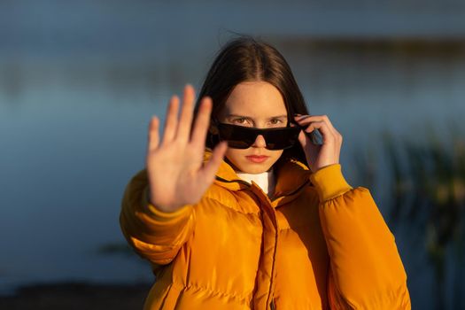 Close up of 12 yars girl show stop gesture sign by hand saying no to domestic violence or abuse, nonverbal language concept.