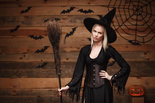 Halloween witch concept - Happy Halloween Sexy Witch holding posing with boring facial expression over old wooden studio background