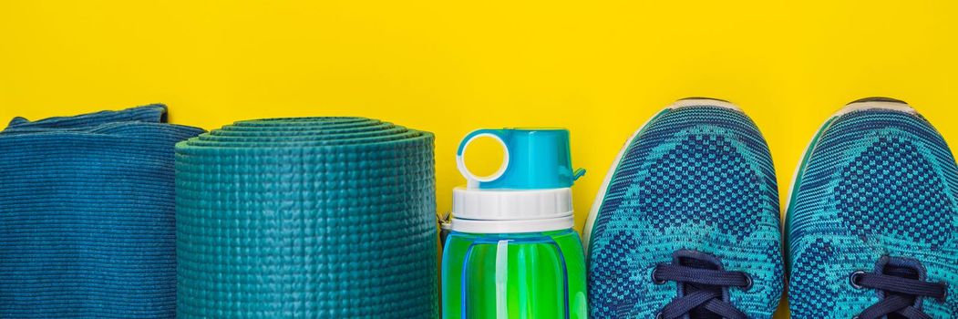 BANNER, LONG FORMAT Everything for sports turquoise, blue shades on a yellow background. Yoga mat, sport shoes sportswear and bottle of water. Concept healthy lifestyle, sport and diet. Sport equipment. Copy space.