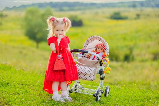 girl with a toy stroller walks in nature