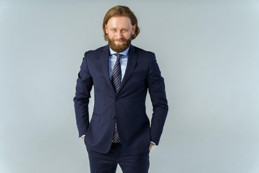 a handsome brutal bearded and long-haired man, a stylish businessman on a white background. High quality photo