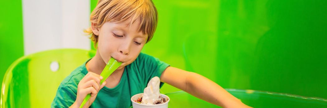 Happy young boy eating a tasty ice cream or frozen yogurt. BANNER, LONG FORMAT