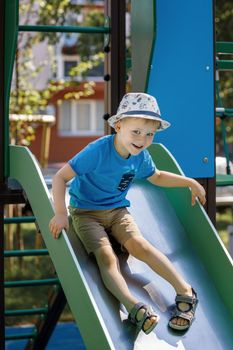 Little boy riding on the slide on children playground. Concept of child development, sports and education.