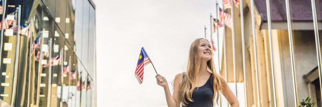 Young woman travels in Malaysia. Holds the Malaysian flag. BANNER, LONG FORMAT