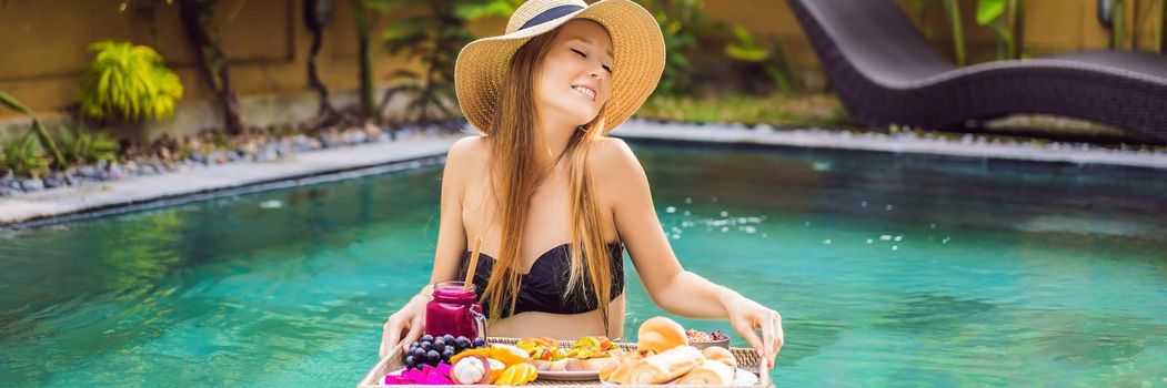 BANNER, LONG FORMAT Breakfast tray in swimming pool, floating breakfast in luxury hotel. Girl relaxing in the pool drinking smoothies and eating fruit plate, smoothie bowl by the hotel pool. Exotic summer diet. Tropical beach lifestyle. Bali Trend.