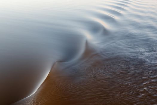 Footprint of the ship. Water twisted by a boat propeller. Beautiful water surface texture. Horizontal photo