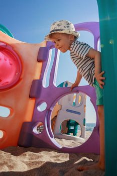 A cute smiling boy playing on an outdoor playground on the beach