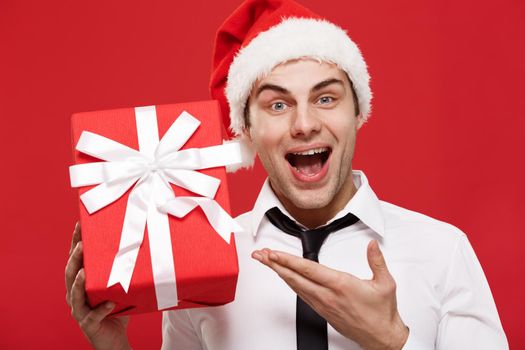 Christmas Concept - portrait close-up Santa christmas businessman over red background holding red gift.