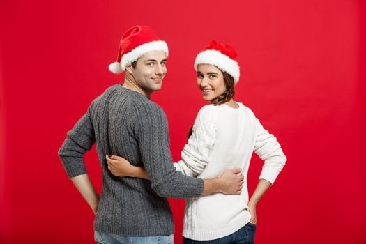 Christmas Concept - back view of portrait lovely young couple hugging over red background.