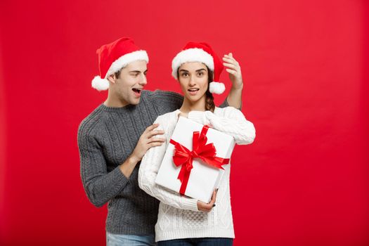 Christmas Concept - handsome young boyfriend in sweater surprise his girlfriend with white gift.