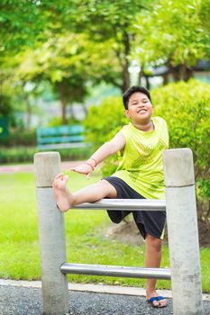 Asian sport boy stretching on iron bar in garden.