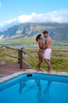 couple man and women in the swimming pool of their lodge on vacation in South Africa looking out over mountains near Hermanus Western Cape
