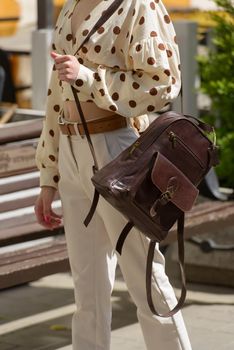 Woman with a brown leather backpack with antique and retro look. Outdoors photo.