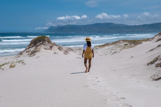 Cape Nature Walker Bay beach near Hermanus Western Cape South Africa. white beach and blue sky with clouds, sand dunes at the beach in South Africa, woman walking at white beach