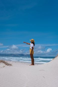 Cape Nature Walker Bay beach near Hermanus Western Cape South Africa. white beach and blue sky with clouds, sand dunes at the beach in South Africa, woman walking at white beach