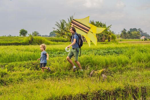 Dad and son launch a kite in a rice field in Ubud, Bali Island, Indonesia.