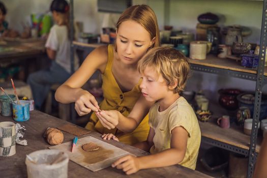 mother and son doing ceramic pot in pottery workshop.