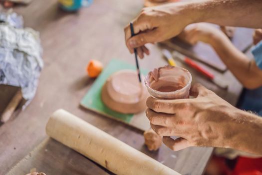 mother and son doing ceramic pot in pottery workshop.