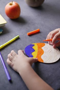 child girl drawing on easter egg wooden block ,