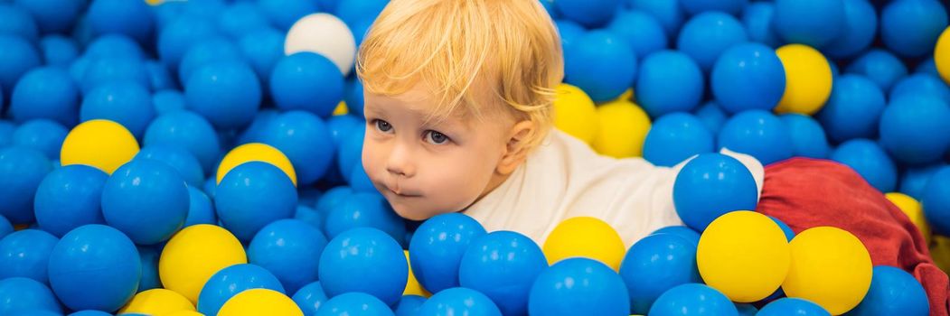 BANNER, LONG FORMAT Child playing in ball pit. Colorful toys for kids. Kindergarten or preschool play room. Toddler kid at day care indoor playground. Balls pool for children. Birthday party for active preschooler.