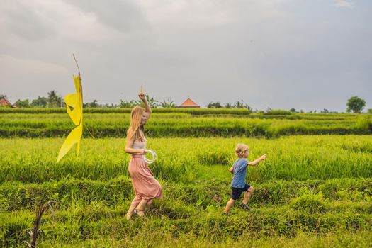 Mom and son launch a kite in a rice field in Ubud, Bali Island, Indonesia.