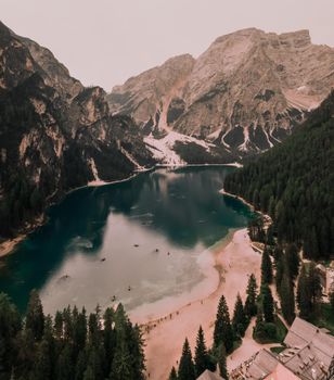 A large clear azure aquamarine green lake with brown wooden boats. High snow-capped stone mountains. Aerial top view from drone.