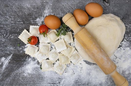 top view rolling pin with tomatoes, dough, eggs, flour and ravioli