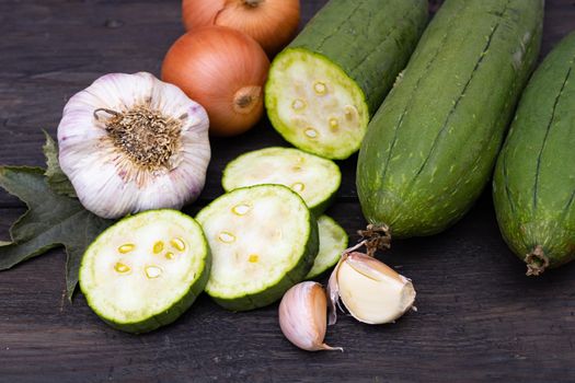 cuisine with luffa garlic and onion on rustic wooden background