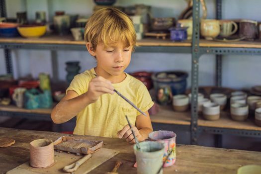 Boy doing ceramic pot in pottery workshop.