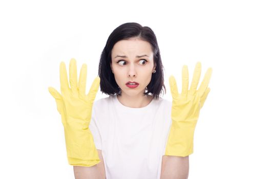 brunette woman in fear looks at her hands in gloves for washing dishes. High quality photo