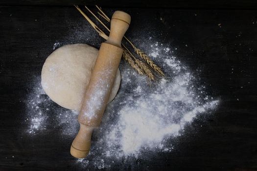 stick with wheat flour dough on rustic wood. concept of kneading