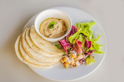 Hummus with tortillas on a white table.