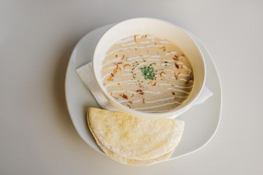 Puree soup with bread on white table.