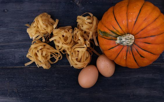Cooking background with pumpkin noodles on wood