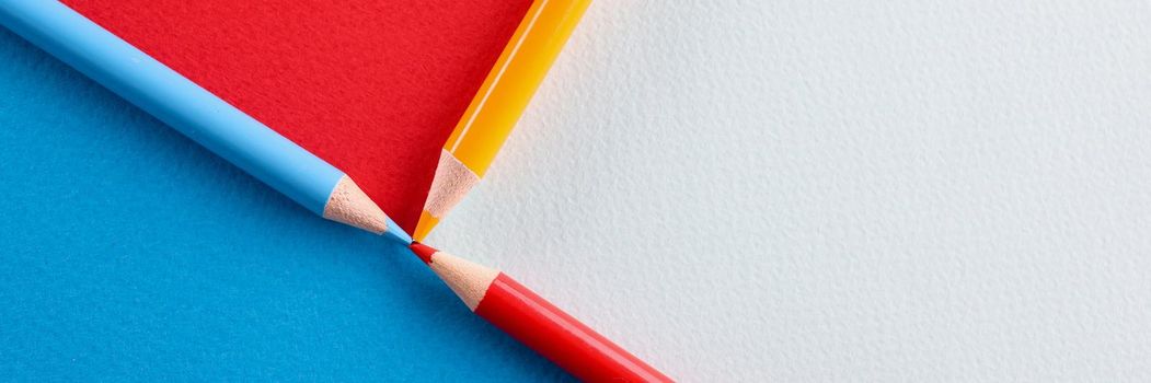 Multicolored pencils lying on paper background closeup. Creative concept