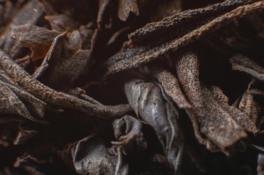 Black loose leaf tea as a background. Texture of dry black tea leaves. Dark background. Extreme macro mode. black leaf tea closeup.