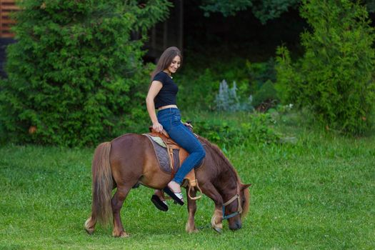 girl riding a pony on a green lawn