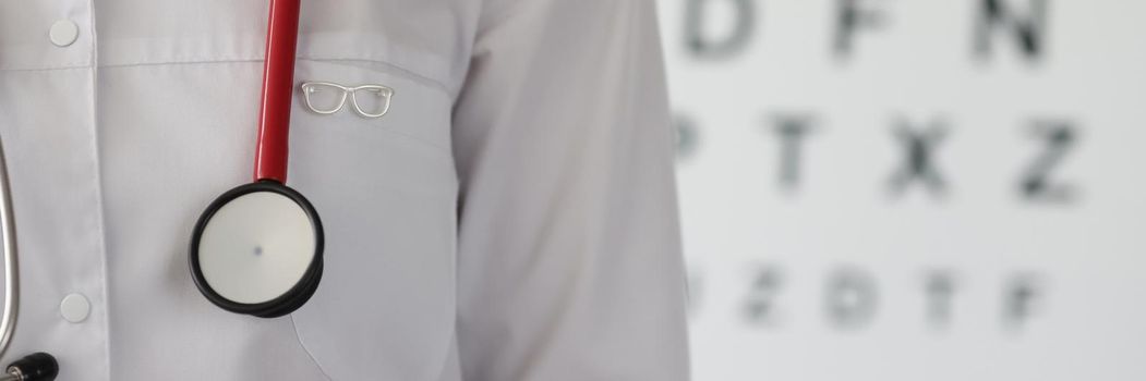 Doctor ophthalmologist with glasses icon standing on background of vision measurement table closeup. Visual acuity test concept