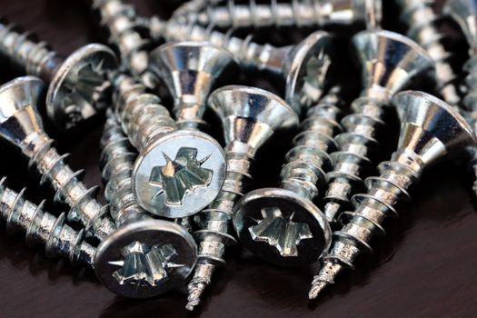 A pile of screws on the black table. Close up