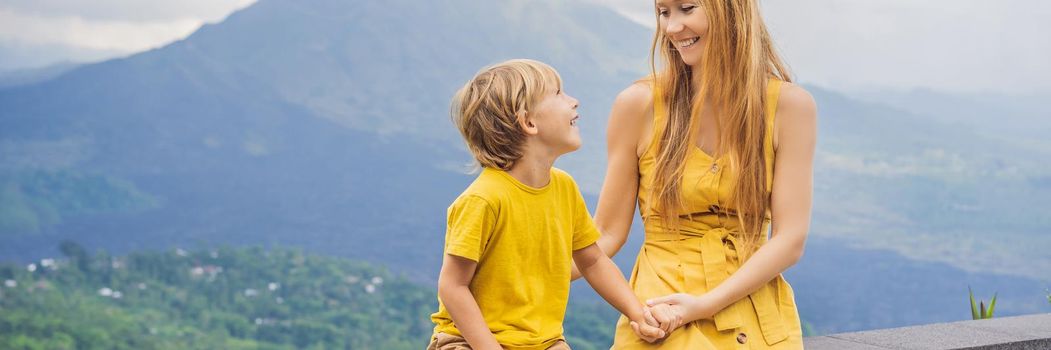 Mom and son tourists on background looking at Batur volcano. Indonesia. Traveling with kids concept. BANNER, LONG FORMAT