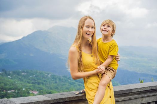 Mom and son tourists on background looking at Batur volcano. Indonesia. Traveling with kids concept.