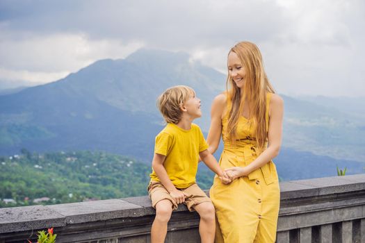 Mom and son tourists on background looking at Batur volcano. Indonesia. Traveling with kids concept.
