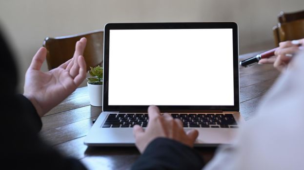 Cropped shot of two young business colleagues discussing financial online information on laptop together.