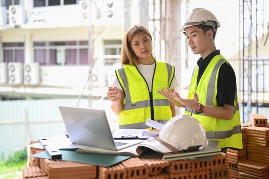 Civil engineer and specialists working, checking plan together at construction site.