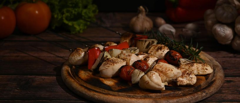 Shish kebab with cherry tomato and sweet pepper and onions on wooden plate. Barbecue, food, holiday concept.