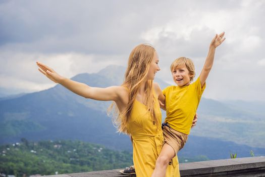 Mom and son tourists on background looking at Batur volcano. Indonesia. Traveling with kids concept.